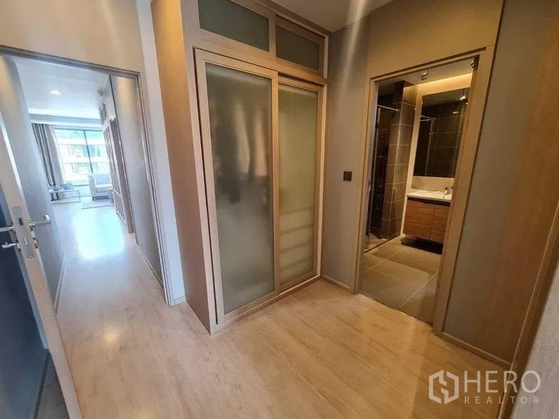 Condominium for sale - Hallway with frosted-glass wardrobe leading to a modern bathroom.
