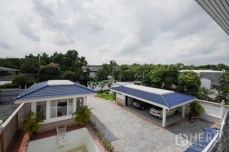 Detached House for rent or sale in Bang Kapi, Bangkok - Spacious paved courtyard with blue-roof carport and guest pavilion in Bang Kapi home.