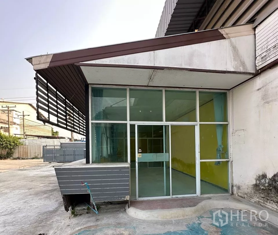 Factory for rent in Samut Prakan - Glass-fronted office entrance attached to the factory building.