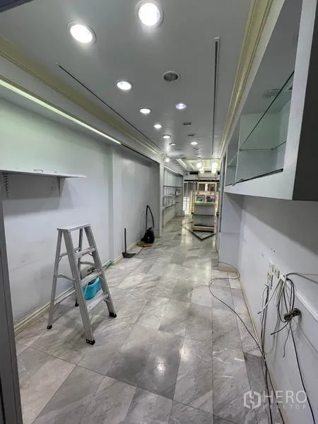 店屋 出租在Bang Rak, Bangkok - 狭长型室内空间，石材地面、筒灯吊顶与搁架施工中。