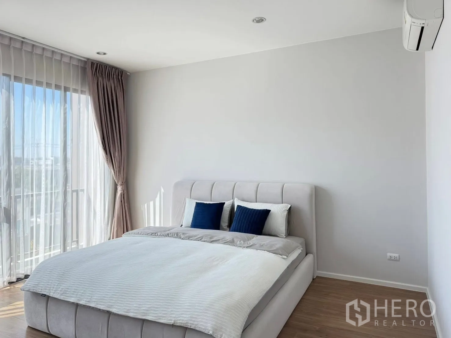 Townhouse for rent in Saphan Sung, Bangkok - Cozy master bedroom corner with upholstered bed, sheer curtains and abundant daylight.