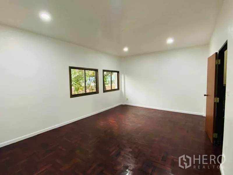 带办公室的家 出租或出售在Suan Luang, Bangkok - 大卧室，三扇窗与深色木地板。