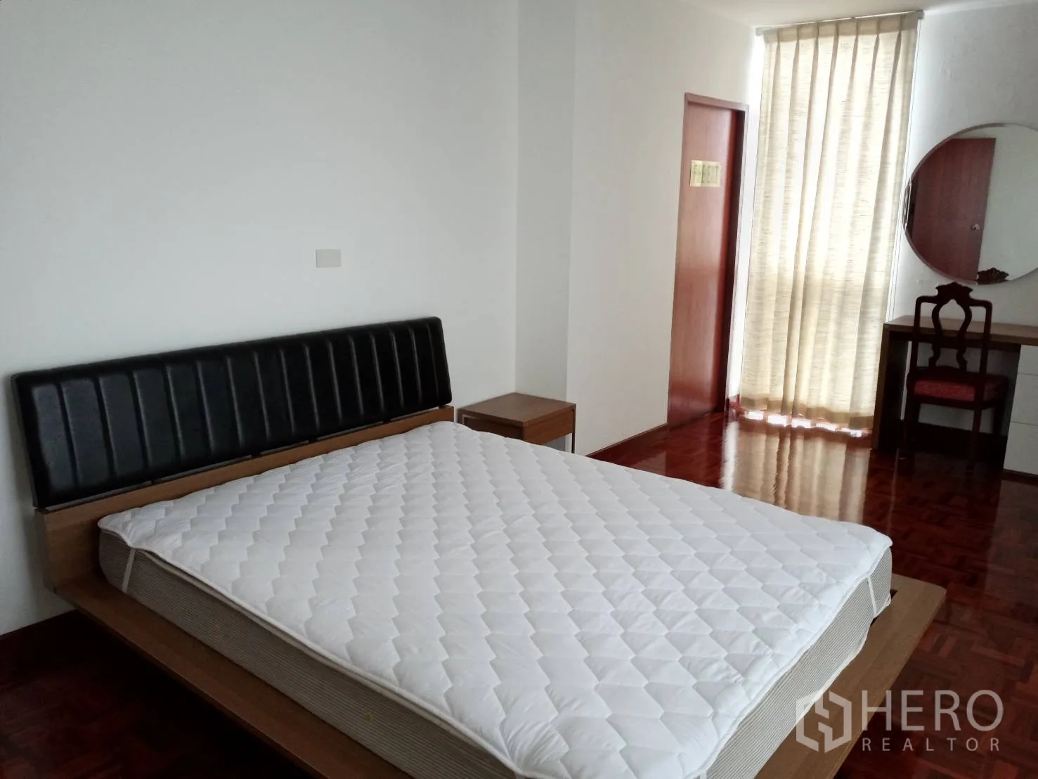 房间 出租在Watthana, Bangkok - 宽敞卧室，配大床、床头柜、梳妆台与透光窗帘。