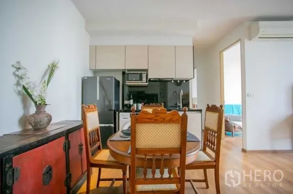 Condominium for sale in Khlong Toei, Bangkok - Dining table for four beside a modern kitchenette with upper cabinets and appliances.
