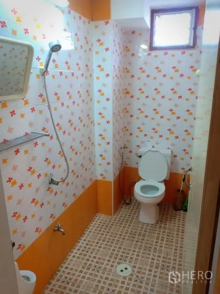 Townhouse for rent in Phra Khanong, Bangkok - Bathroom with shower, toilet and orange floral-patterned tiles.