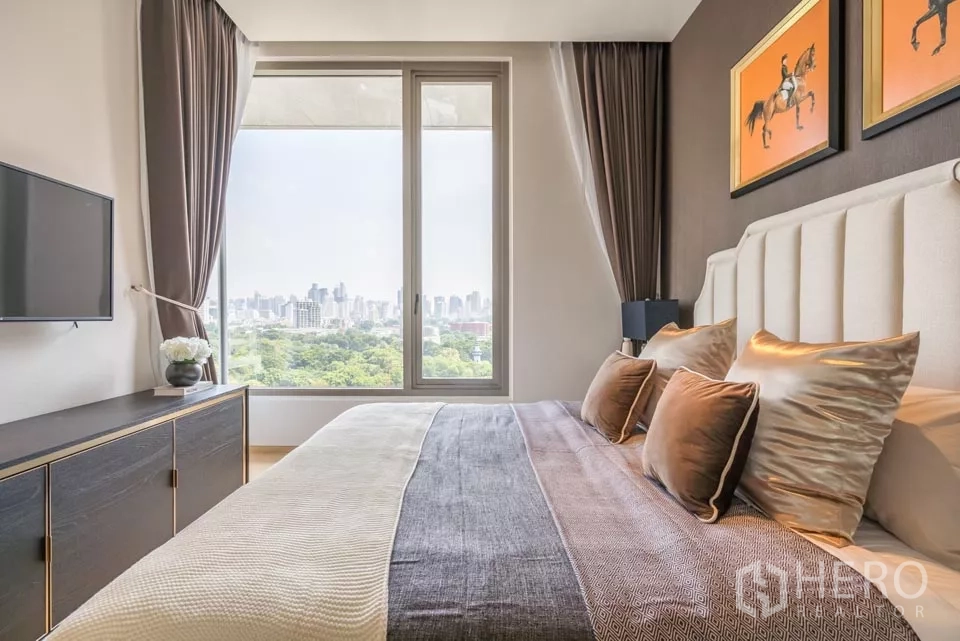 公寓 出租或出售在Bang Rak, Bangkok - 卧室侧景，大窗外是郁郁葱葱的公园与天际线。