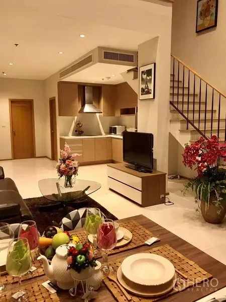公寓 出租在Khlong Toei, Bangkok - 用餐区望向客厅与开放式厨房，旁有楼梯，整体暖色调。