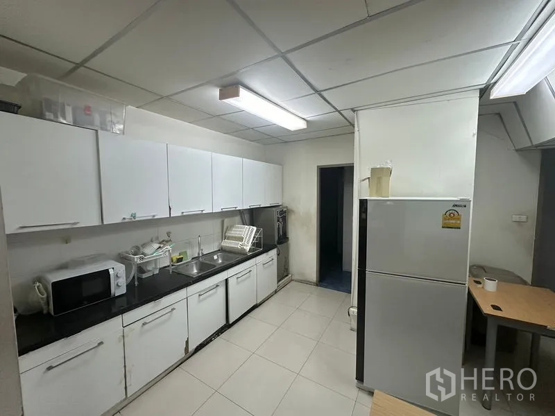 Office Space for rent - Office pantry with white cabinets, black countertop and refrigerator