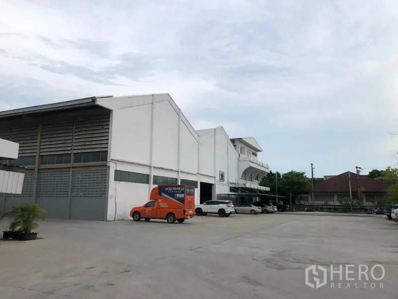 Factory for rent in Mueang Samut Prakan, Samut Prakan - Industrial complex frontage with ample parking and loading area for vans and trucks.