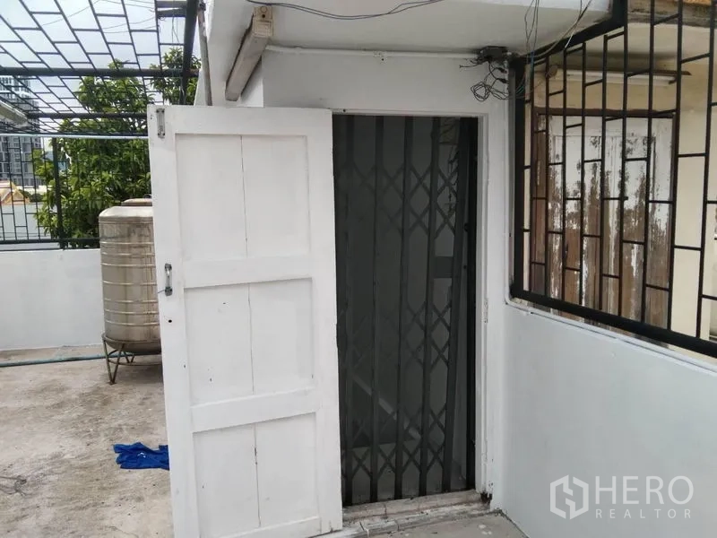 店屋 出租在Watthana, Bangkok - 屋顶入口，配白色门和可伸缩安全栅门。