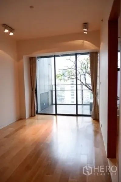Condominium for sale in Sathon, Bangkok - Bright bedroom facing glass doors that open to a city-view balcony.