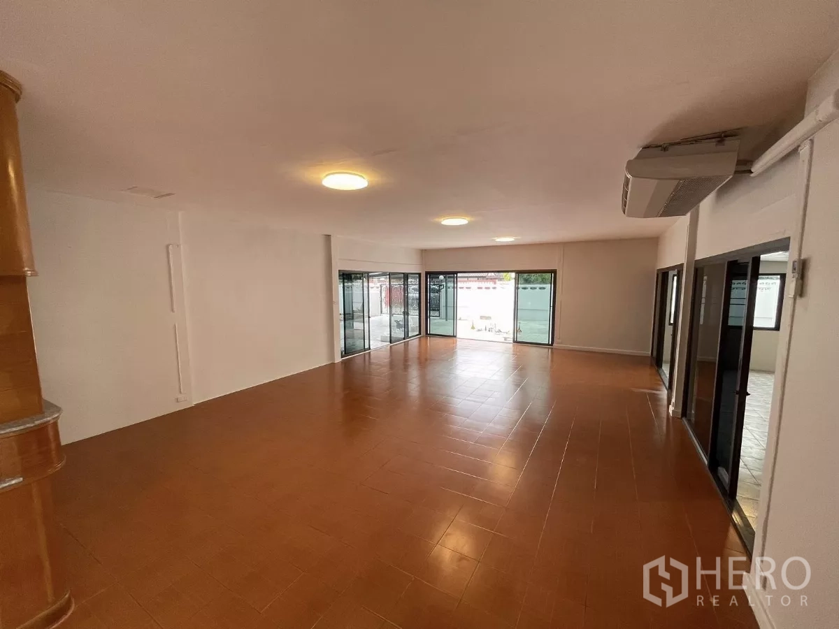 Home Office for rent in Din Daeng, Bangkok - Extra‑large living or work space with brown floor tiles and a wall of sliding doors to the patio.