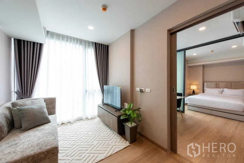 คอนโด ให้เช่าในHuai Khwang, Bangkok - ห้องนั่งเล่นอบอุ่นพร้อมโซฟา ชั้นทีวี และทางเข้าห้องนอนหลัก