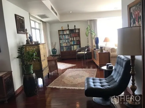 Condominium for rent or sale in Watthana, Bangkok - Spacious living area with hardwood floors, bookshelves and lounge seating.
