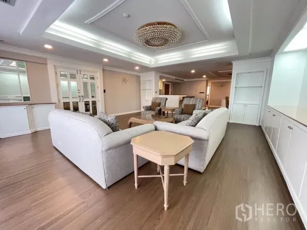 公寓 出租在Watthana, Bangkok - 宽敞客厅，格栅吊顶与水晶吊灯，木地板与成套沙发。
