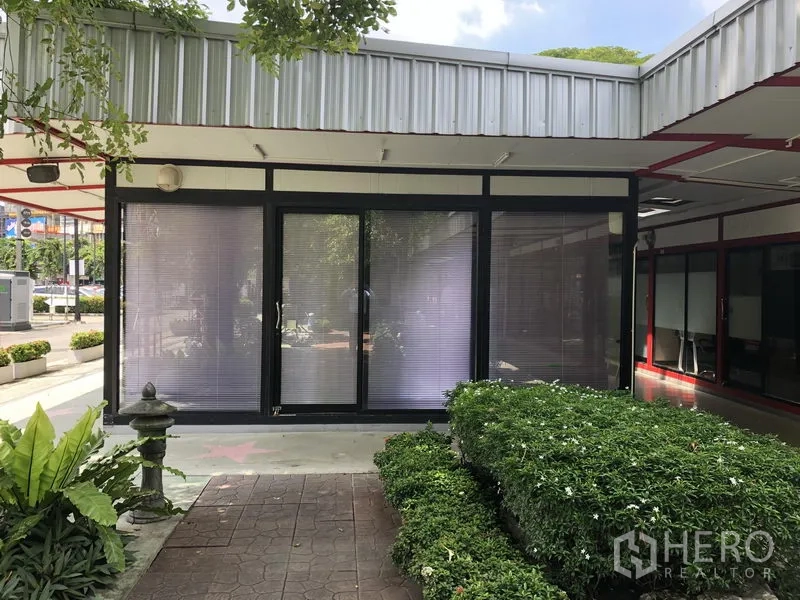Office Space for rent in Wang Thonglang, Bangkok - Exterior of compact office unit with sliding glass doors, blinds, and a landscaped walkway in Wang Thonglang.