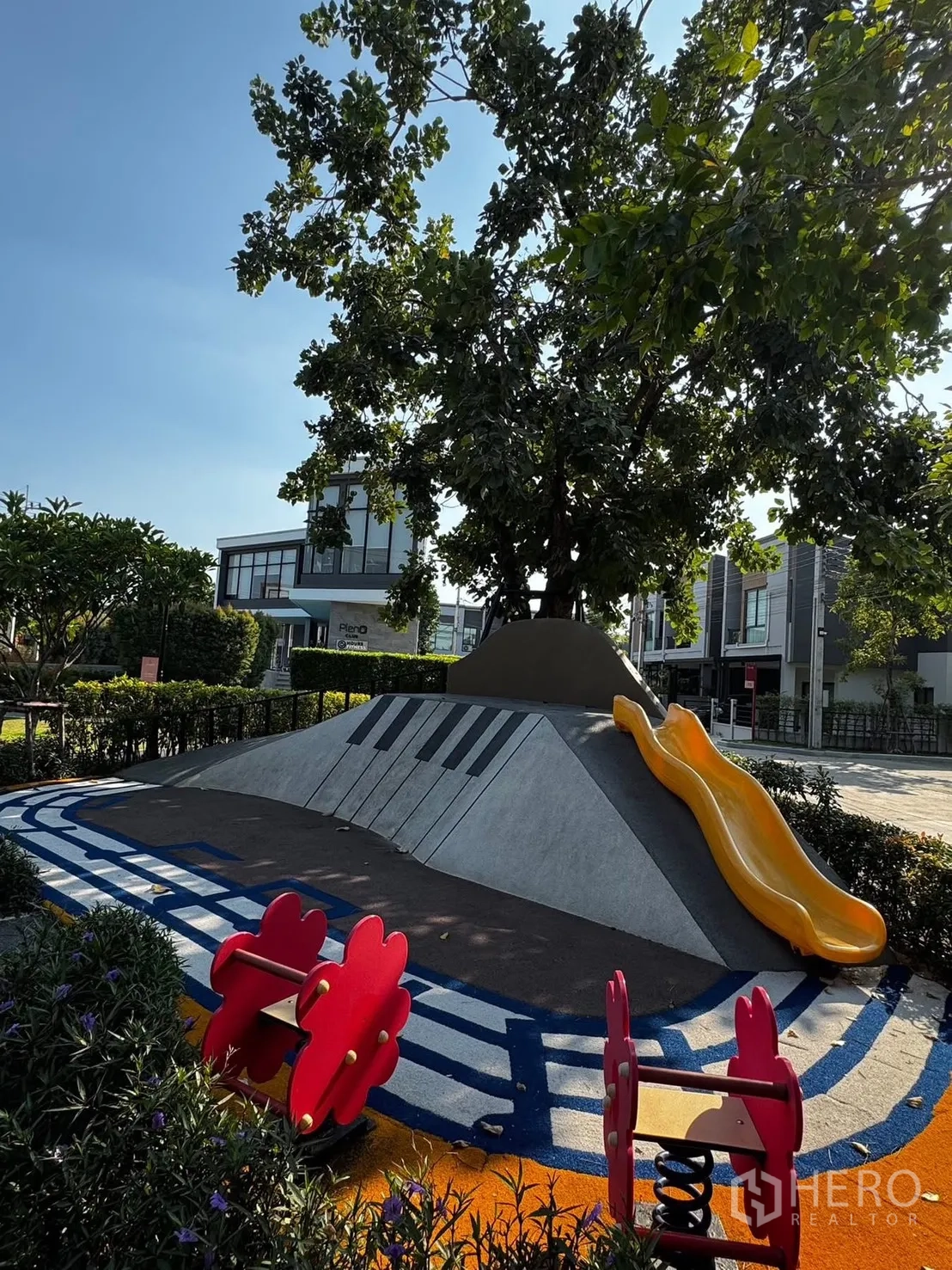 ทาวน์เฮาส์ ให้เช่าในBang Phli, Samut Prakan - สนามเด็กเล่นส่วนกลางธีมดนตรีพร้อมสไลเดอร์สีเหลือง ใต้ร่มไม้ ข้างทาวน์เฮ้าส์สมัยใหม่