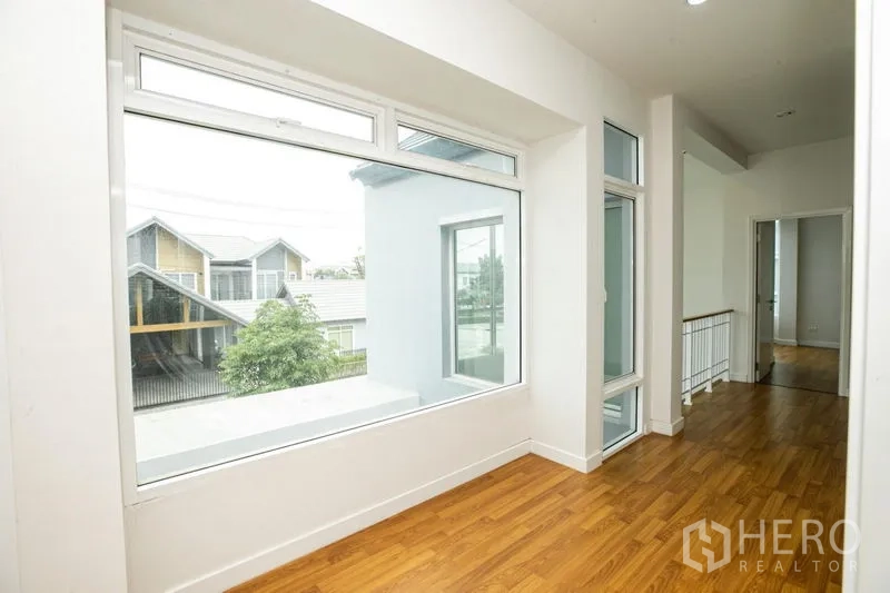 Detached House for rent or sale in Lam Luk Ka, Pathum Thani - Upstairs nook with a large picture window and access to a balcony.