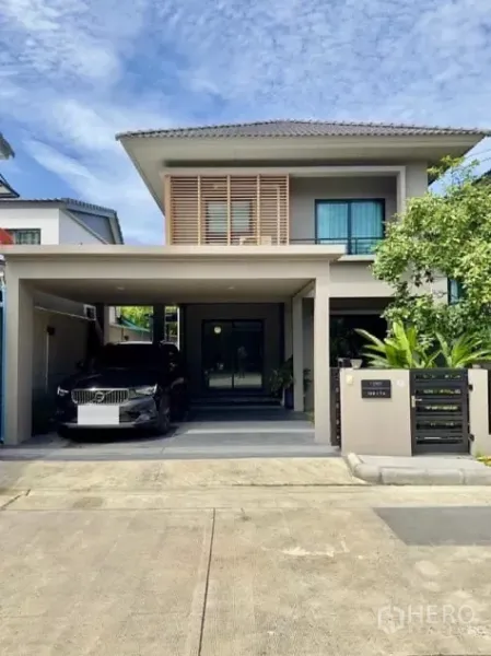 独立式住宅 出租在Samut Prakan - 现代两层独立屋外观，带有遮棚车位与前院围栏。