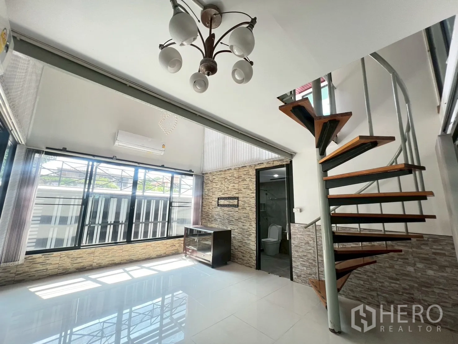 Detached House for rent or sale in Wang Thonglang, Bangkok - Living area corner with spiral stairs and doorway to a bathroom.
