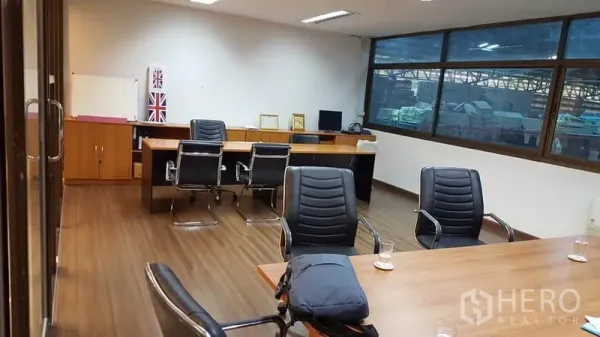 Warehouse for rent or sale - Bright office inside the warehouse with desks, meeting table, wood flooring and large windows.