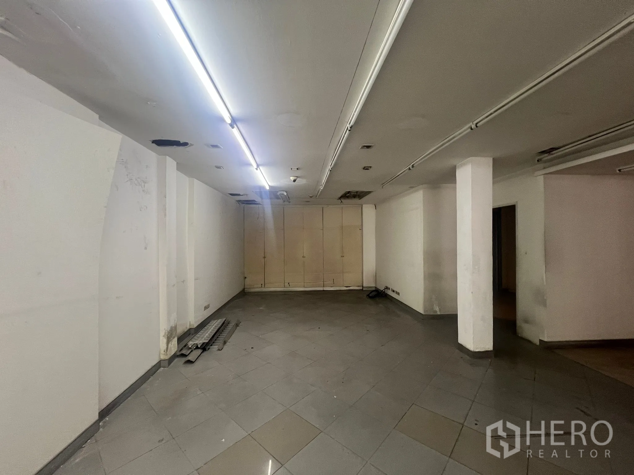 店屋 出租在Watthana, Bangkok - 后场开放区，带储物柜、白墙与中央立柱及条形灯。