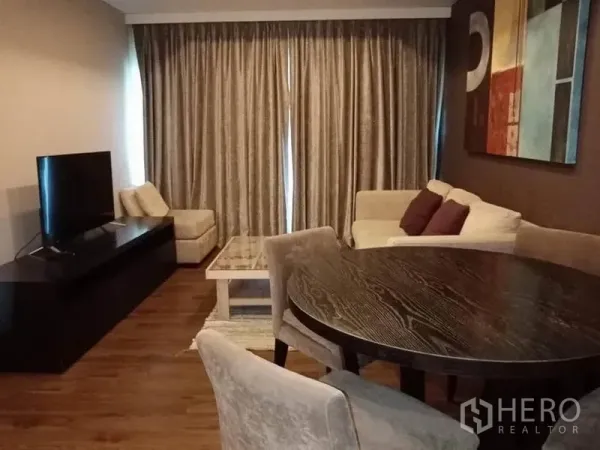 คอนโด ให้เช่าในSathon, Bangkok - ห้องนั่งเล่นคอนโดสาทรแบบโมเดิร์น มีโซฟา โต๊ะทานข้าวทรงกลม ชั้นวางทีวี และผ้าม่านสูงจรดพื้น