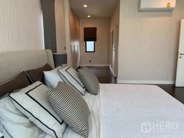 Detached House for rent or sale in Bang Kapi, Bangkok - Master suite angle showing upholstered bed, fitted wardrobes and air-conditioning.
