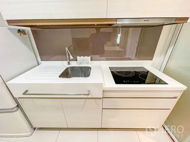 Condominium for sale - Kitchen close-up showing sink, ceramic hob and glossy backsplash.