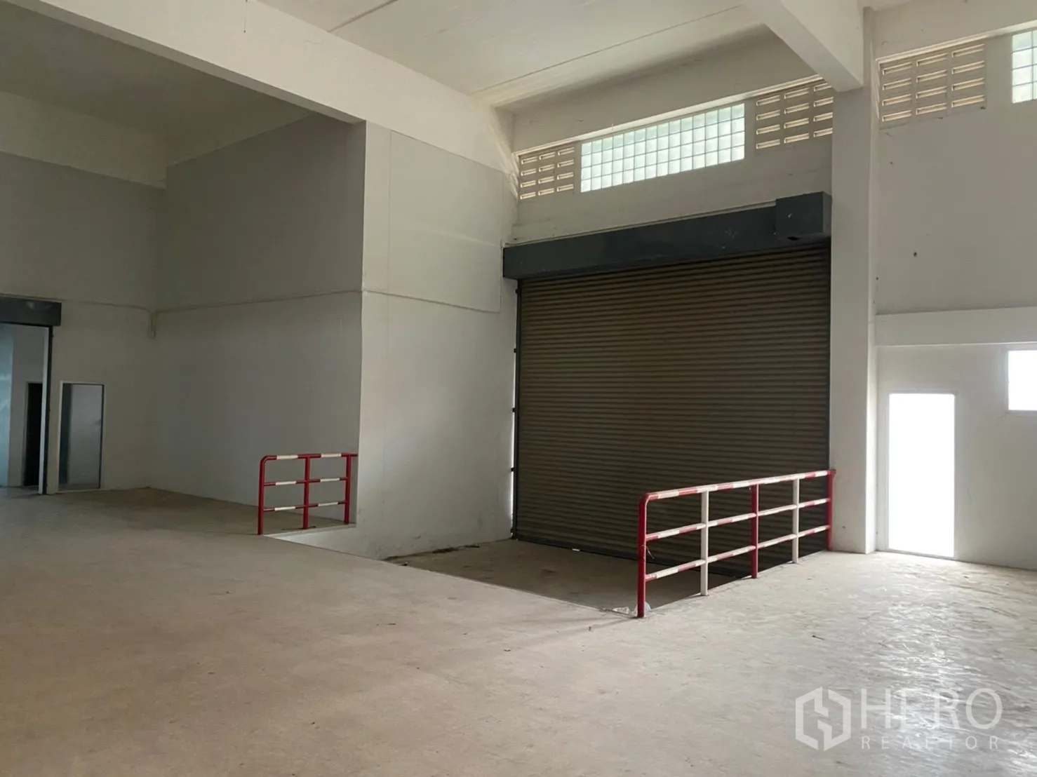 Warehouse for rent in Lat Krabang, Bangkok - Loading area featuring a high roller shutter door and red safety railings.