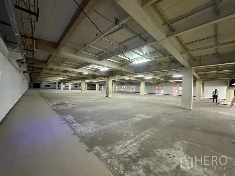 Factory for rent or sale in Thanyaburi, Pathum Thani - Vast open manufacturing floor with concrete surface, columns, and fluorescent lighting.