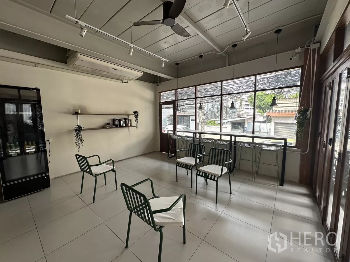 Retail Space for rent in Watthana, Bangkok - Bright seating area featuring floor-to-ceiling windows, a bar counter with stools, tiled floors and wall shelving.