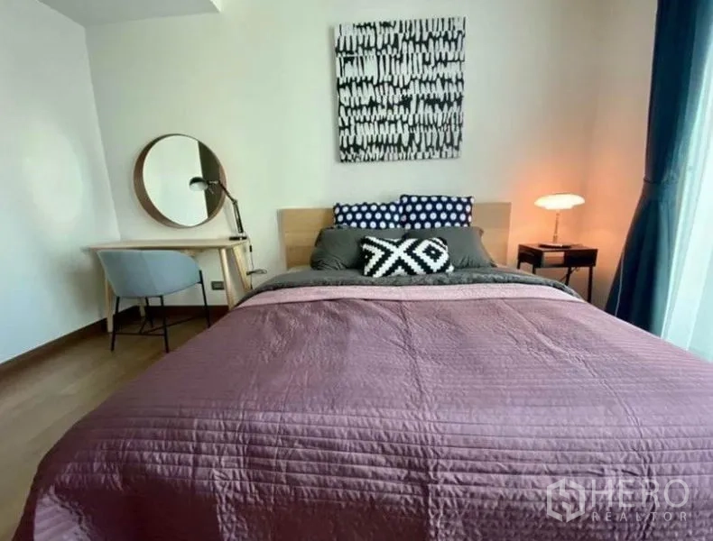 Condominium for rent in Watthana, Bangkok - Cozy bedroom with double bed, study desk, round mirror and bedside lamp.