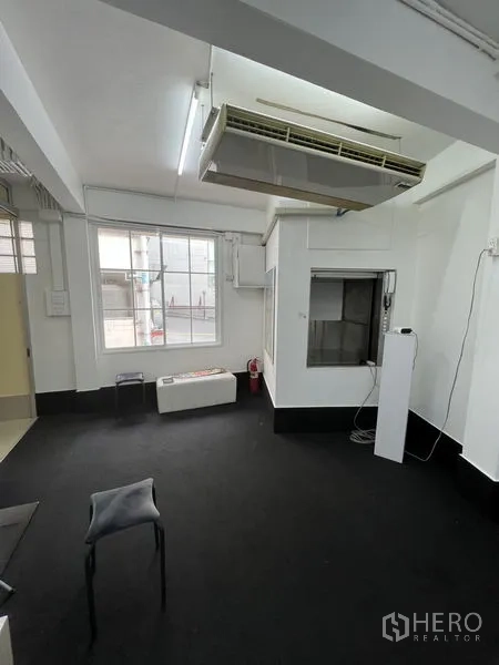 Shophouse for rent in Khlong Toei, Bangkok - Flexible white room with window, large ceiling air conditioner and dark carpet.