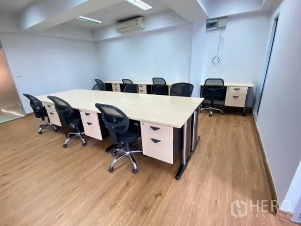 办公空间 出租在Khlong Toei, Bangkok - 开放式办公室，配置长条工位与人体工学椅，木质地板与壁挂空调。