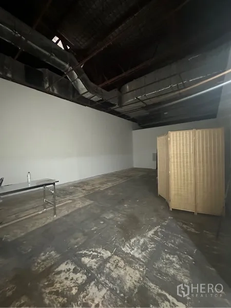 Retail Space for rent - Open retail space showing exposed HVAC, white walls and a movable partition screen.