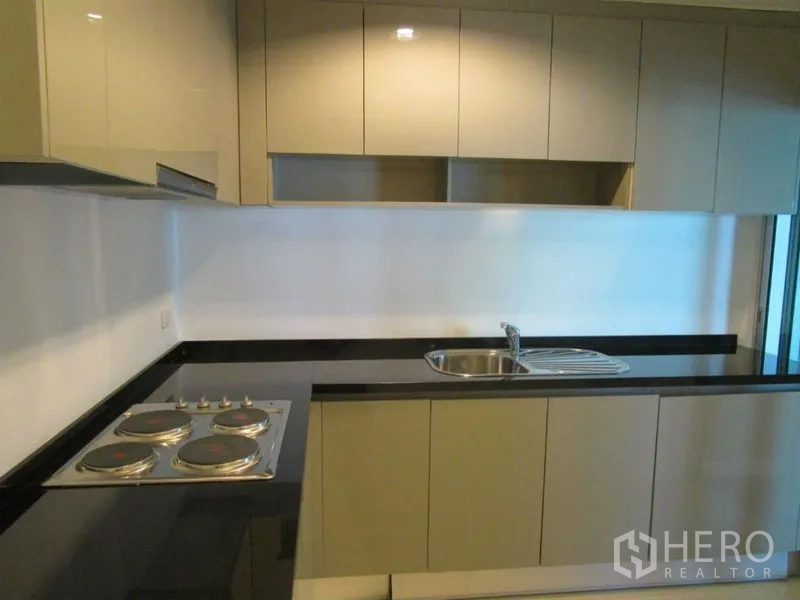คอนโด ขายในHuai Khwang, Bangkok - ครัวบิวต์อิน เคาน์เตอร์หินสีดำ เตาไฟฟ้า และตู้ลอย