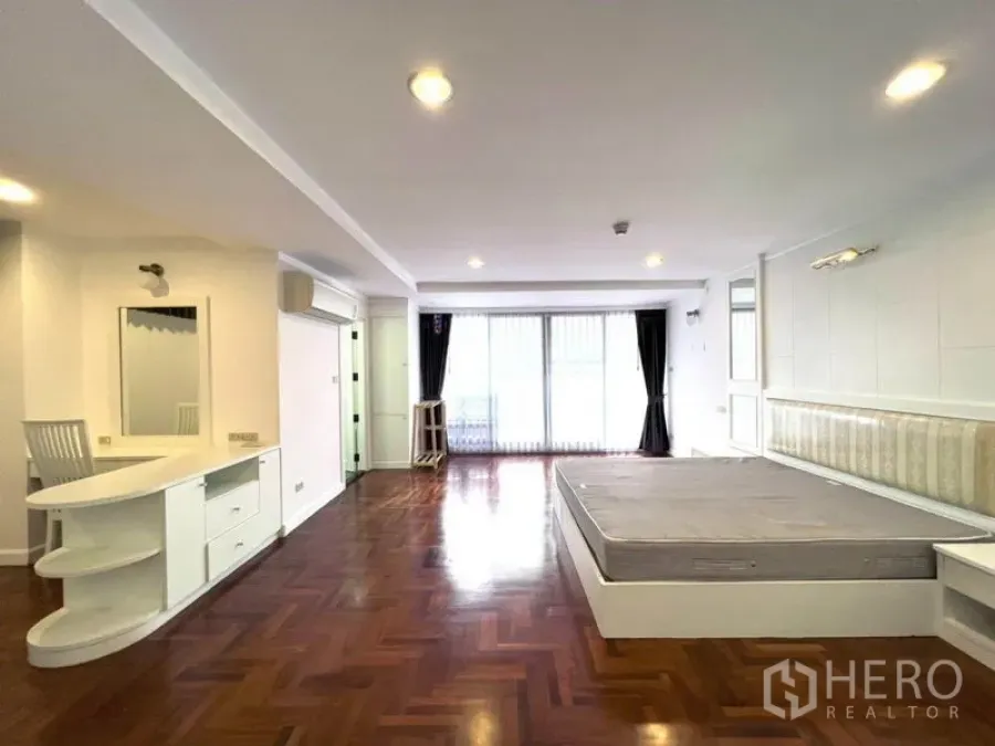 公寓 出租在Watthana, Bangkok - 宽敞卧室，拼花木地板，内置梳妆台，推拉门通往阳台。