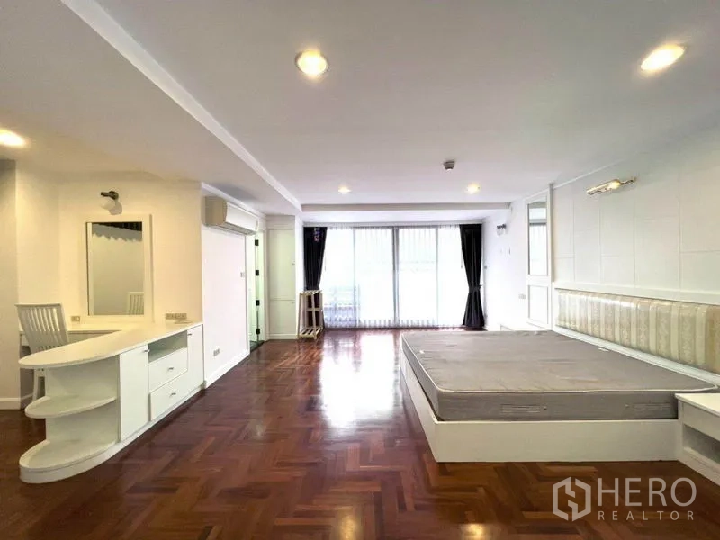 公寓 出租在Watthana, Bangkok - 宽敞卧室，拼花木地板，内置梳妆台，推拉门通往阳台。