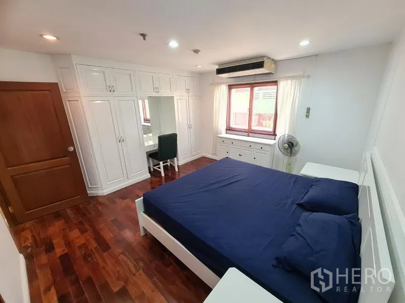 Condominium for rent or sale in Watthana, Bangkok - Spacious master bedroom with extensive built-in wardrobes, dressing desk and large window.