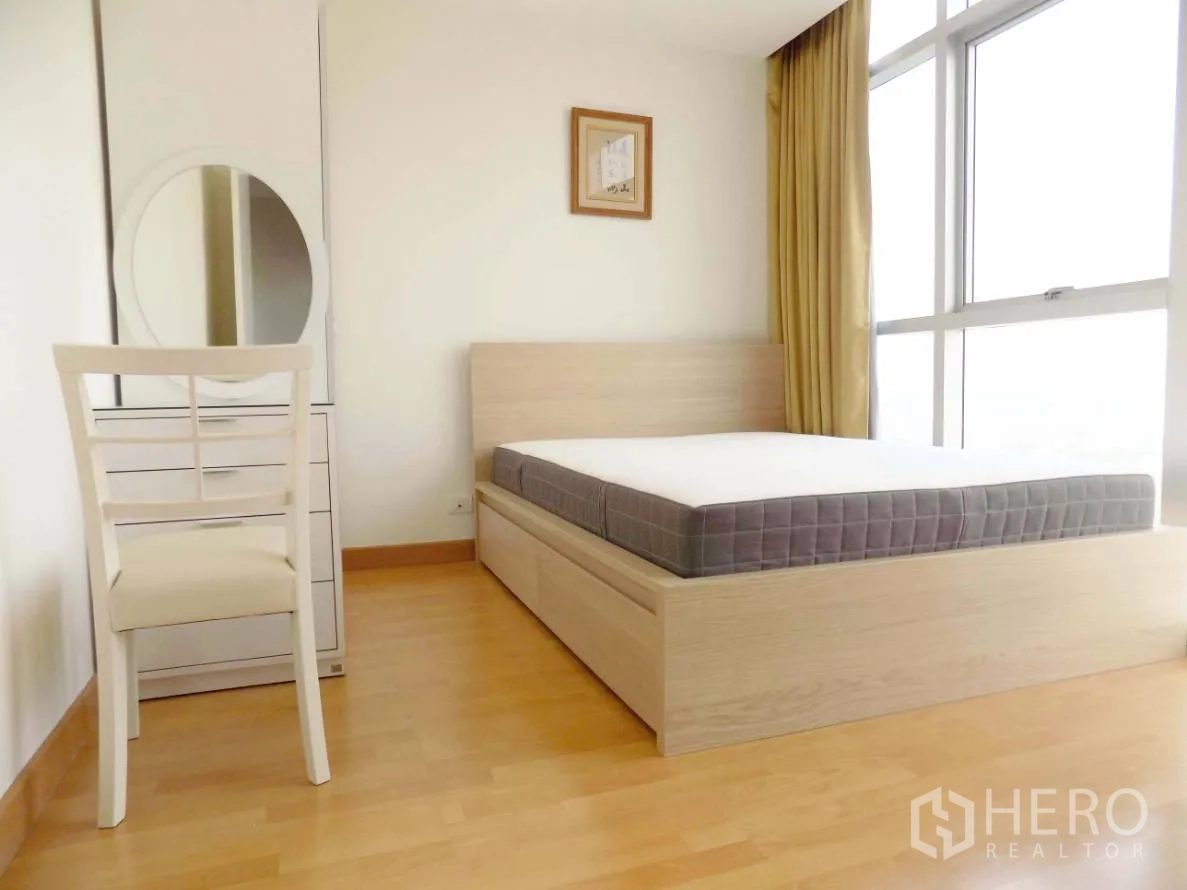 Condominium for rent or sale in Khlong Toei, Bangkok - Bright second bedroom with large window, light wood bed, vanity and warm wood flooring.