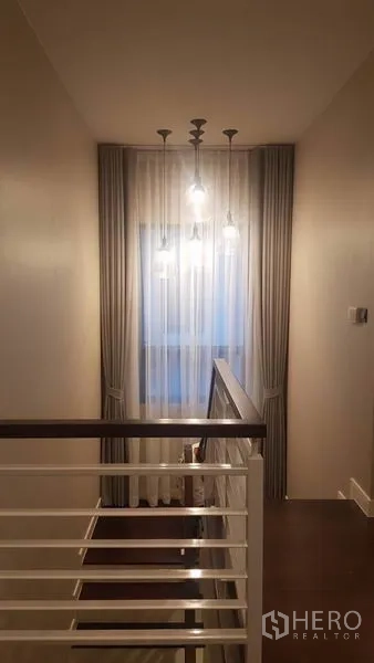 Detached House for rent in Saphan Sung, Bangkok - Stair landing with pendant lights, sheer curtains and a white handrail.