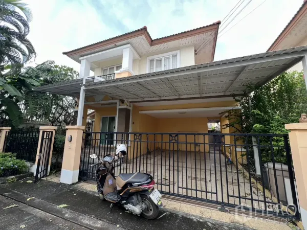 บ้าน ให้เช่าในBang Kapi, Bangkok - ด้านหน้าบ้านเดี่ยวพร้อมประตูรั้วและหลังคาที่จอดรถ ล้อมด้วยต้นไม้ร่มรื่น
