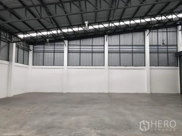 Warehouse for rent or sale in Lam Luk Ka, Pathum Thani - Empty warehouse space showing polished concrete floor, ventilated wall panels and skylight strips.