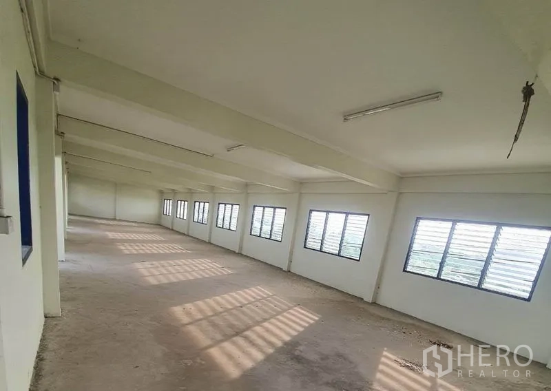 Factory for rent in Bang Bua Thong, Nonthaburi - Long ventilated corridor with louver windows and fluorescent lighting.