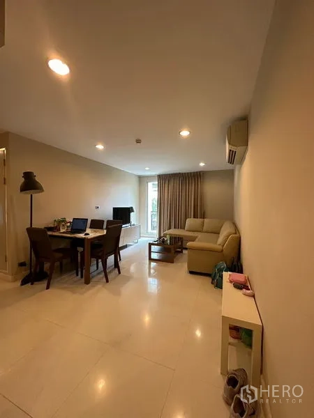 Condominium for rent in Khlong Toei, Bangkok - Bright open-plan living and dining room with L-shaped sofa, dining table and balcony access.