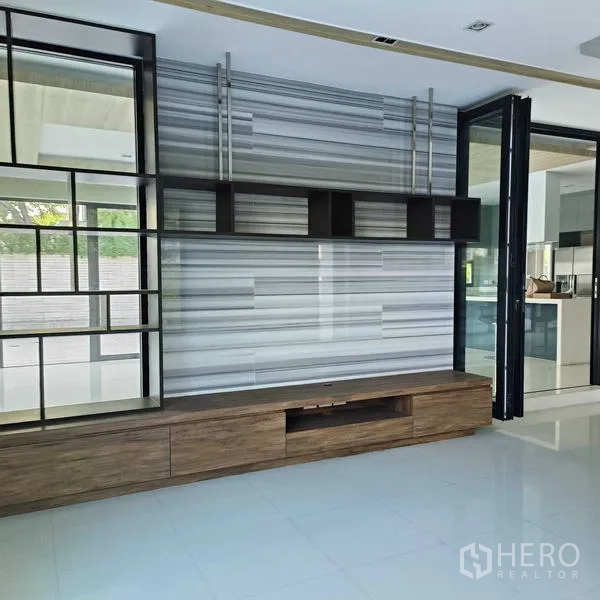 独立式住宅 出租或出售在Mueang Nonthaburi, Nonthaburi - 电视背景墙与开放置物架，旁接通往厨房的玻璃隔断。