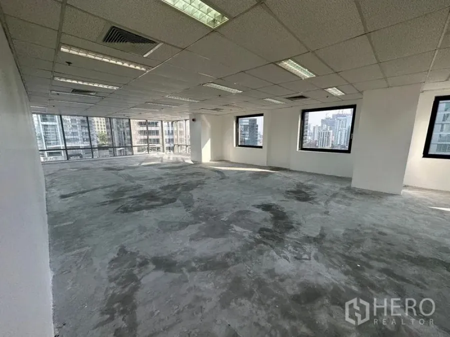 Office Space for rent - Open-plan office floor with drop ceiling lights, AC vents, and multiple city-view windows.