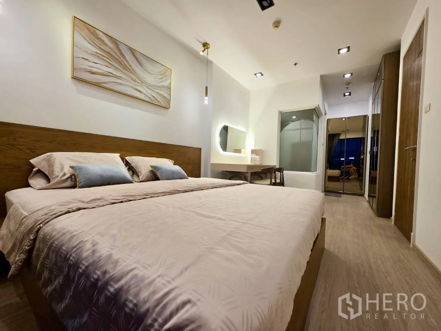 คอนโด for rent in Huai Khwang, Bangkok - ห้องนอนเตียงคิงไซส์ หัวเตียงไม้ โต๊ะเครื่องแป้ง และผนังกระจกเชื่อมห้องน้ำ