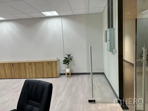 Office Space for rent in Sathon, Bangkok - Entrance corner featuring glass door, wood storage cabinets and a potted plant on light laminate flooring.